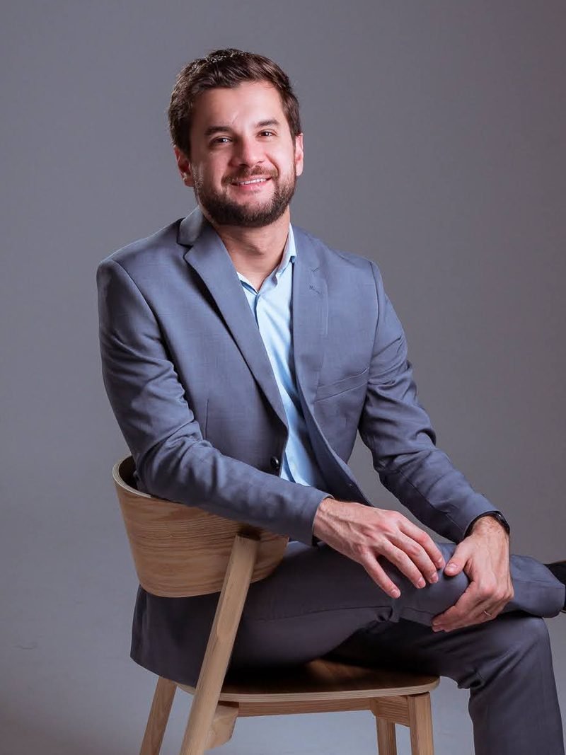 Dr. Paulo Othávio Almeida sentado, de terno cinza, em plano aproximado